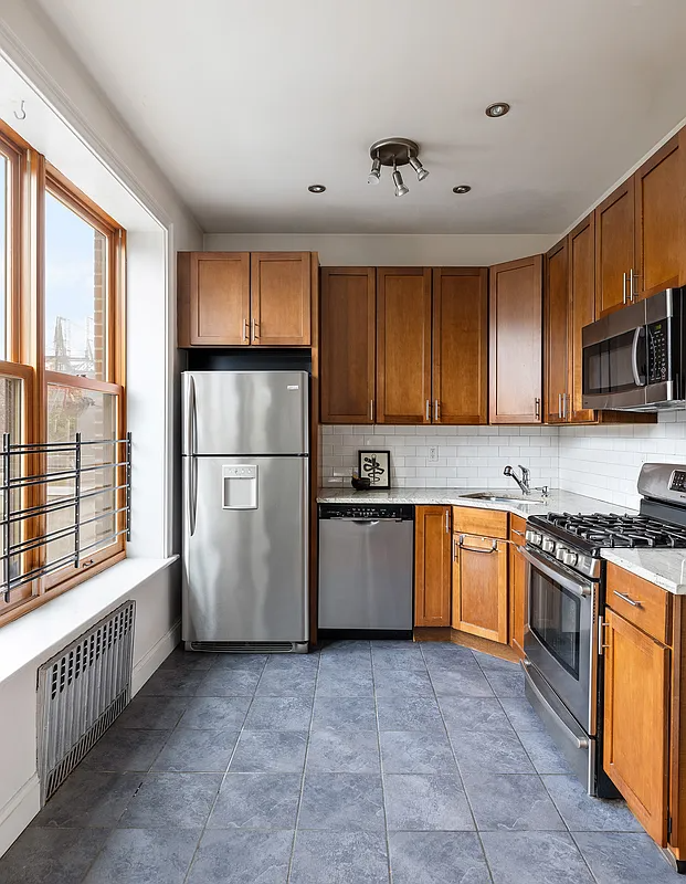 kitchen with wood cabinets, white subway tile, gray floor tile