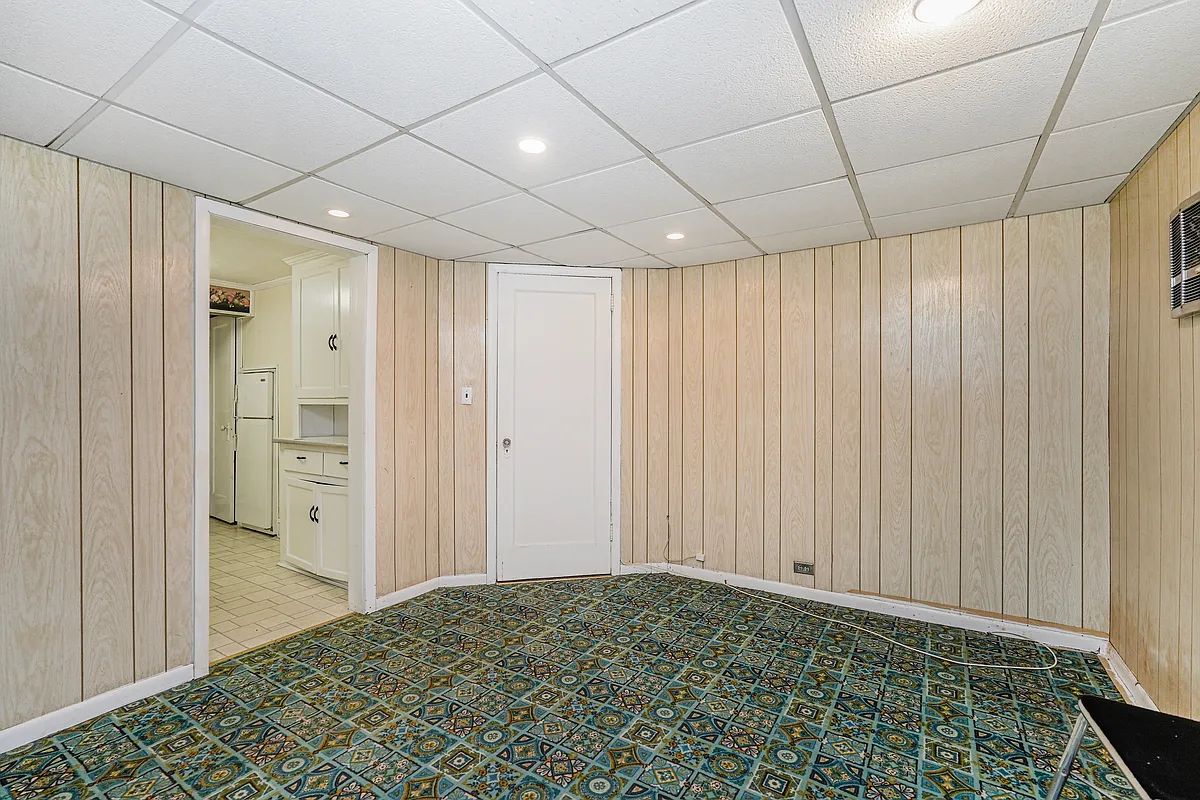 garden level room with paneling, drop ceiling, and carpet