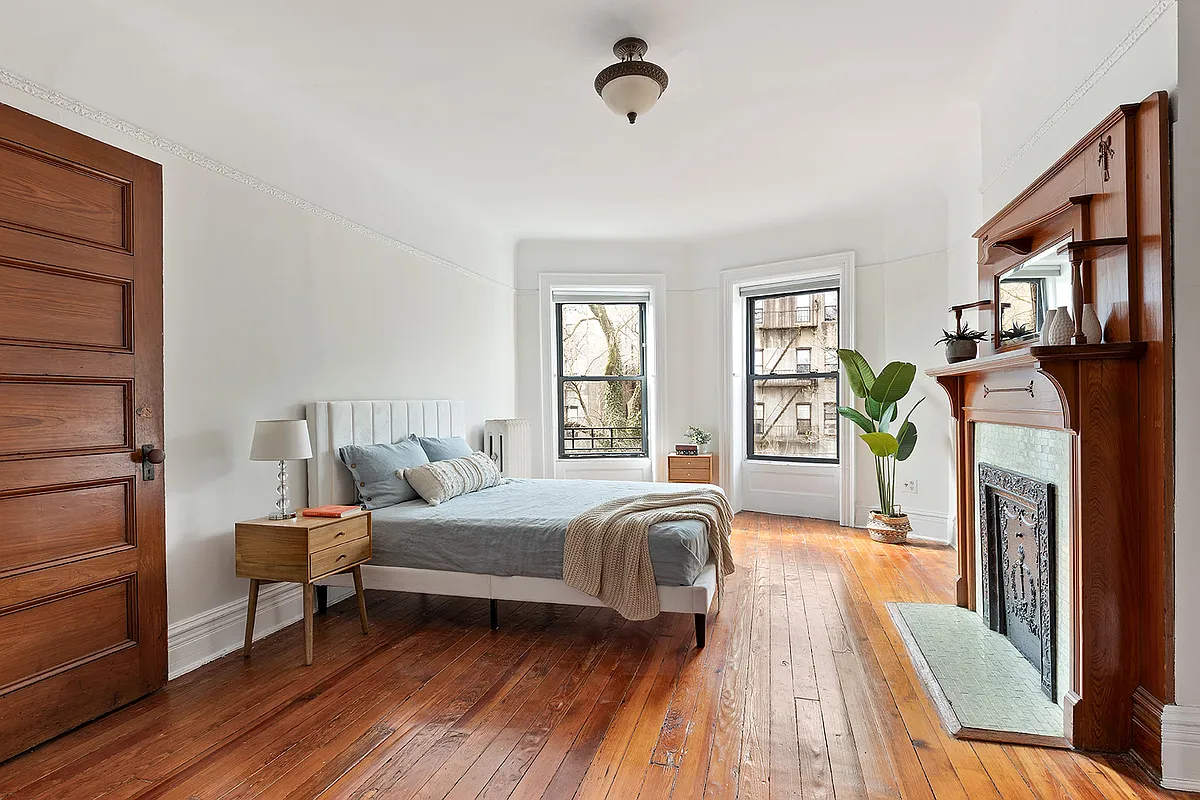 bedroom with wood floor, mantel