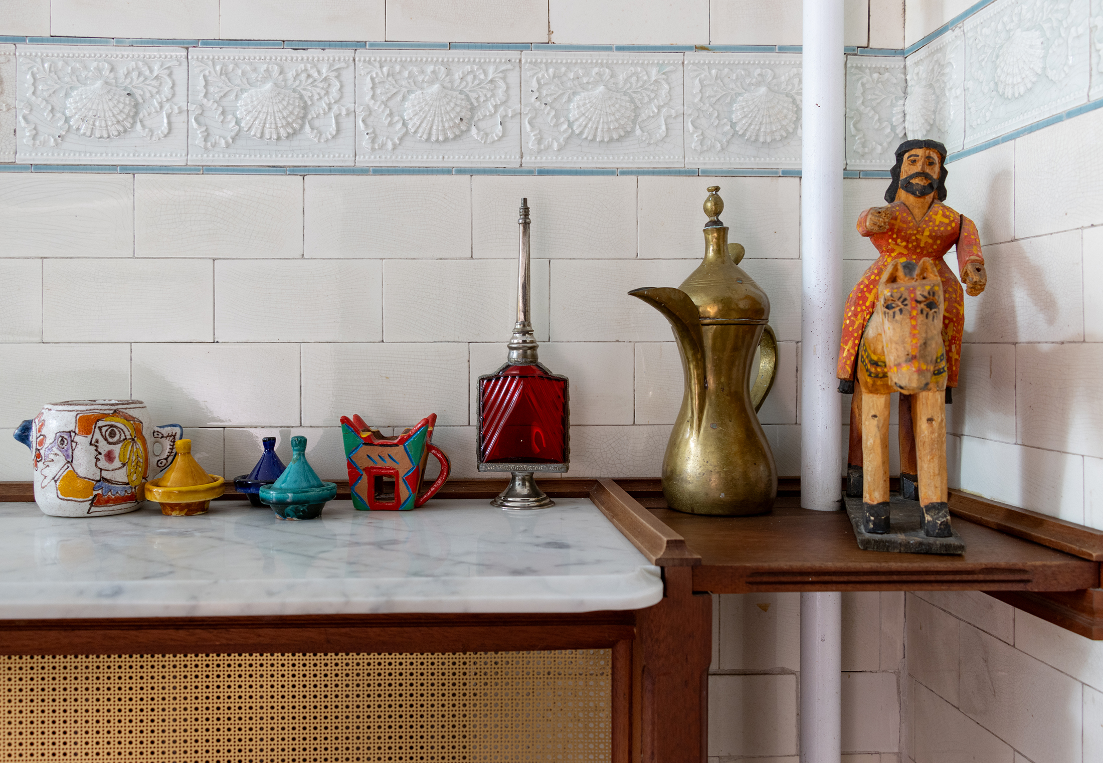 bathroom with shell tile border, artwork on shelf